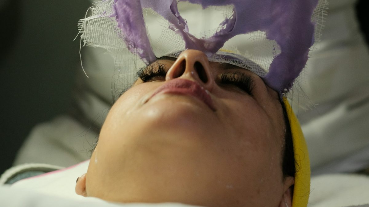 Sala de atendimento de clínica de estética com maca, equipamento e iluminação suave