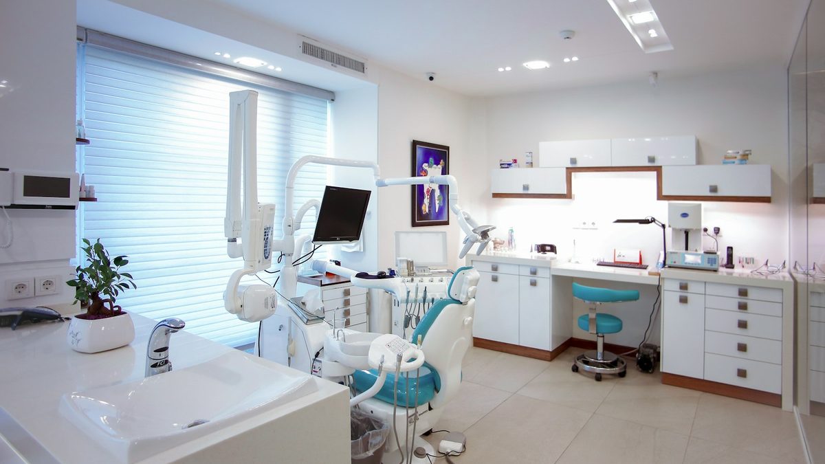Consultório odontológico moderno com cadeira, refletor e equipamento organizado