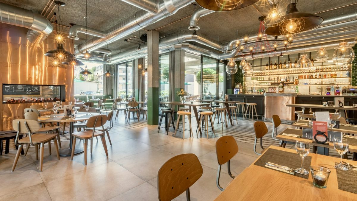 Salão de restaurante com mesas postas e clientes durante o serviço do almoço